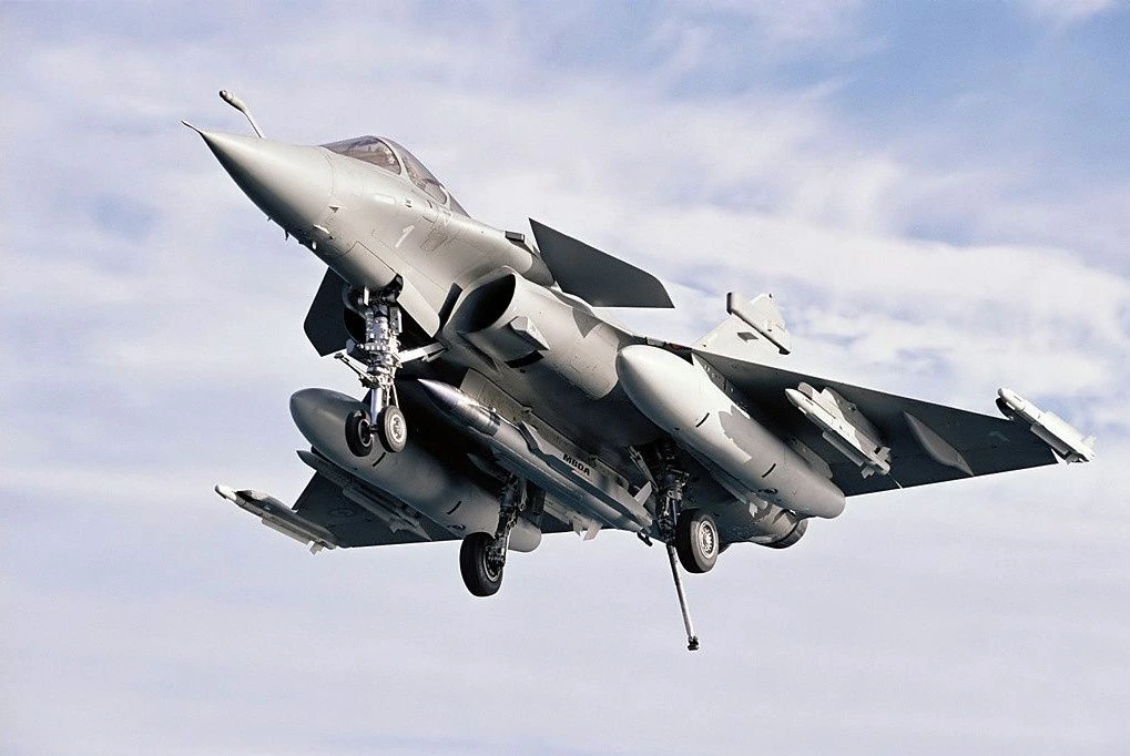Un Rafale Marine en vol, train sorti, sous voilure chargée de missiles et de bidons